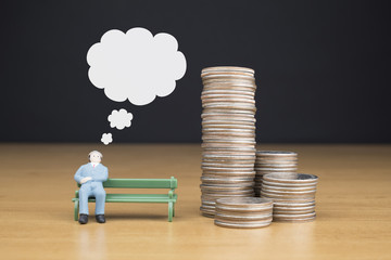 BUSINESSMAN SITTING ON A GREEN BENCH NEAR BY PILE OF US QUARTER COINS WITH THOUGHT BUBBLE ON TOP OF...