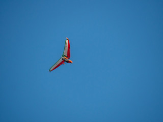 Hang glider up in blue sky on sunny day flying.