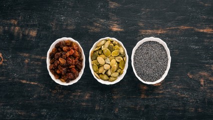 Raisins, sunflower seeds and poppy seeds. On a black wooden background. Top view. Free copy space.