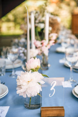 Long festive table with blue tablecloth decorated with flowers and candles