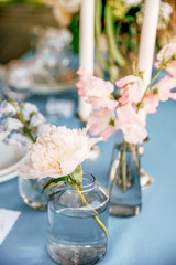 Peach color peony on small glass jar with water