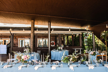 Long festive table with blue tablecloth decorated with flowers and candles