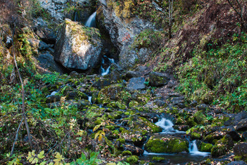 Landscape mountain river in autumn forest at sunlight. Fast jet of water at slow shutter speeds give a beautiful magic effect.