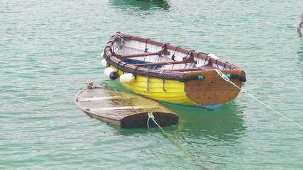 A small wooden rowing boat filled with water and sinking in St Ives harbour, Cornwall.
