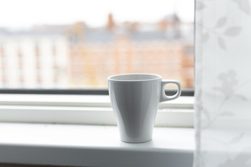 A cup of coffee on the windowsill. Big window. Scandinavian style