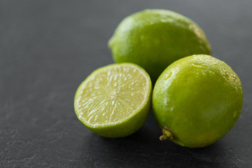 food, healthy eating and vegetarian concept - close up of limes on slate table top