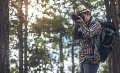 hiker holding his camera with backpack in the forest