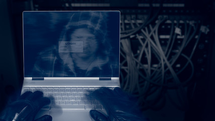 Hacker with laptop on a dark background of structured cabling. Close-up of male hands in black...