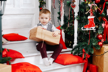 Obraz na płótnie Canvas Little boy opens a New Year's gift near the Christmas tree