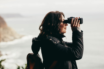 Female hiker enjoying spectacular view through binoculars