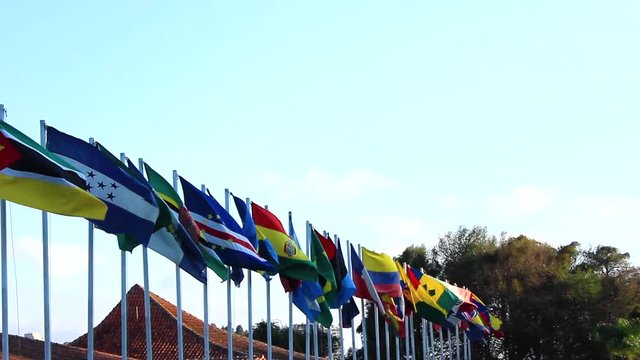 Locked shot side angle of countries flags blowing in slow motion in the wind. Flags are placed in a row.