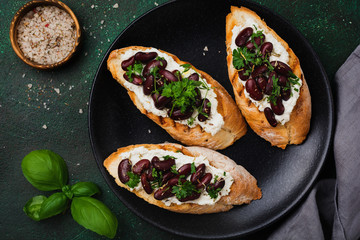 Sandwich with red beans, garlic, olive oil and curd cheese on dark background. Mexican Cuisine. Top view.
