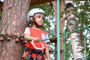 Portrait of cute little boy and girl walk on a rope bridge in an adventure rope park.