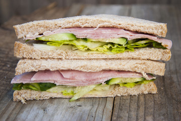 Club Sandwich with Ham and Vegetables. Rustic wooden background.