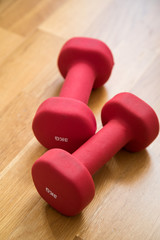 Zwei rote Kurzhanteln auf Holz für Fitness Training