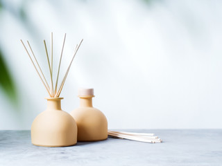 Fototapeta na wymiar aroma reed diffuser home fragrance with rattan sticks on a light background with palm leaves and shadows.