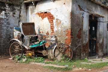 The old and abandoned rickshaw and bicycle in front of a gate in Varanasi
