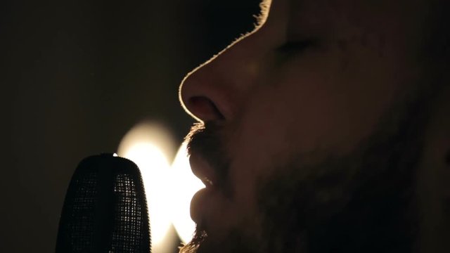 Close up shot of singer in the studio. Close up shot of microphone and man's face