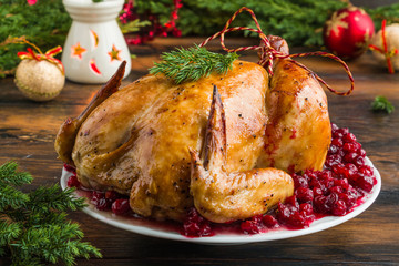 Whole rosted chicken with cranberry sauce on white plate on wooden table with Christmas decoration - 226863816