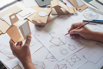 Designer sketching drawing design Brown craft cardboard paper product eco packaging mockup box development template package branding Label . designer studio concept . - Powered by Adobe