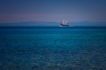 Fishing boat on the blue Aegean Sea in Samothrace Island in Greece with sea gulls surrounding it