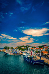 Kamariotissa port harbour on Samothrace Island in Greece during day with a vibrant sky and beautiful colors in the water with lots of boats at the pier