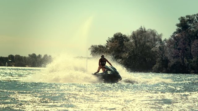 Water rider drive jet skiing on city river. Active man on jet ski having fun on river at sunny day. Extreme water sport in slow motion