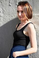 young girl posing against a concrete wall, dressed in black, hard light and shadows