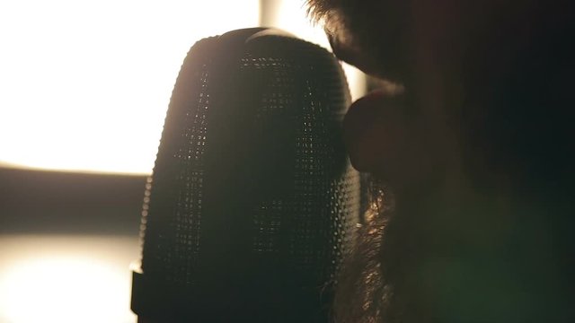 Close up shot of singer in the studio. Close up shot of microphone and man's mouth