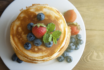 American pancakes with strawberry and blueberry jam, delicious dessert for breakfast, rustic style, wooden background. Copy space.