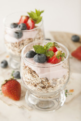 Healthy breakfast, oat meal with fruits: bluebery, strawbery and min, parfait in a glass on a rustic background. Healthy food.