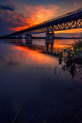 Fototapeta na wymiar Road bridge crossing a river at sunset with beautiful clouds on sky
