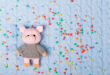 New Year knitted toy pig on a knitted textured and colored balls background. Flat lay, top