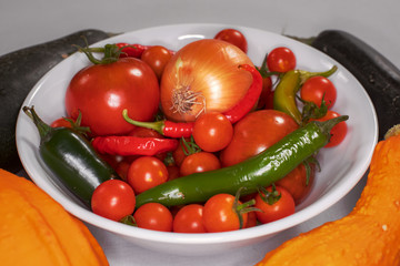 fresh peppers, tomatoes and an onion in a bowl