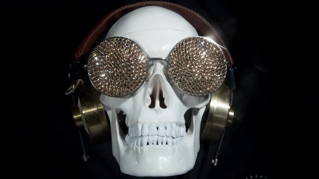 halloween skull wearing headphones and sparkling gold sunglasses