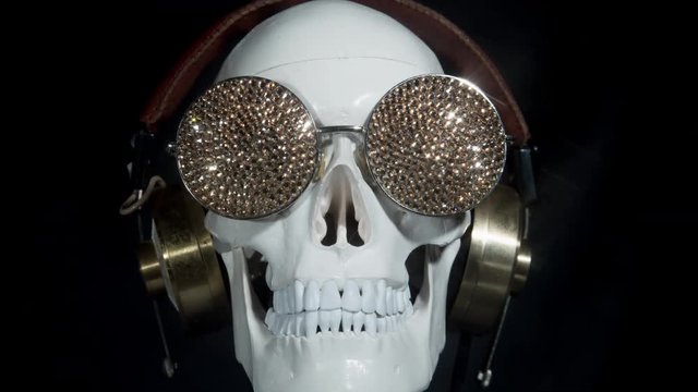 halloween skull wearing headphones and sparkling gold sunglasses