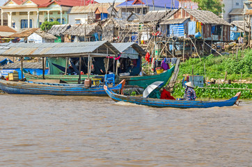 Fototapeta na wymiar Three women rowing a long-tail boat along the banks of Tonle Sap Lake