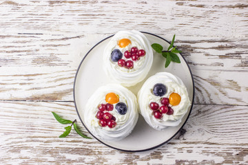 Delicious mini Pavlova meringue cake decorated with fresh red currant and blueberry