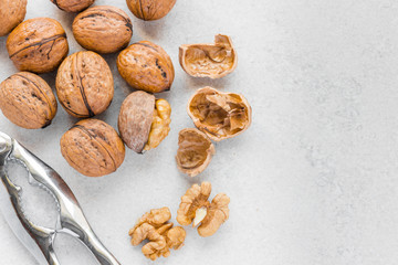 Whole and cracked walnuts next to silver nutcracker