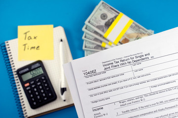 Tax form with calculator, pen, and dollar banknote. Business and tax concept. Tax Time written on...