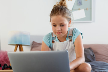 Cute girl using laptop in her bedroom