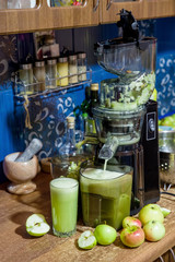 apple juice flowing from the juicer on the table in the kitchen