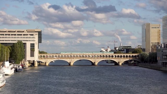 Metro crossing Bercy bridge with French Ministry for the Economy and Finance and National Library of France in background - Paris, France