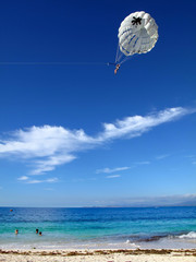 Parasailing, con paracadute grande bianco, e giovani che fanno il bagno su acque verde azzurre
