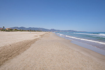 Fototapeta na wymiar landscape beach of Grao of Castellon named PIne or Pinar, in Valencia, Spain, Europe, from sea shore. Blue clear sky, Mediterranean Sea and Benicassim in the horizon