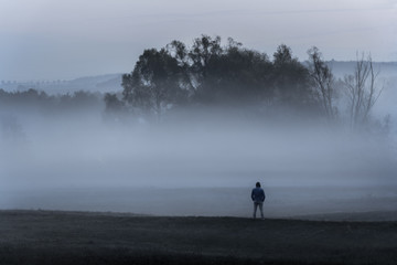 Man standing alone in  the foggy nature
