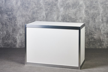 White glass showcase stand against gray textured wall background. International Exhibition...