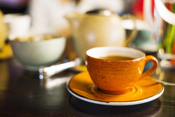 a Cup of tea in the cafe, an orange mug on the table, a mug on the table