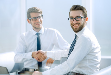 successful employees shaking hands sitting at the Desk