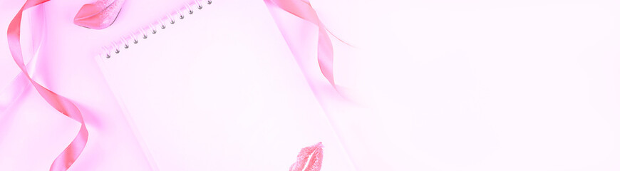 Blank notepad, pink ribbon and lips. Concept of holiday or greetings. Selective focus, top view, flat layout.